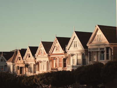 Row of 7 houses in pastel colours, in low sunlight. 