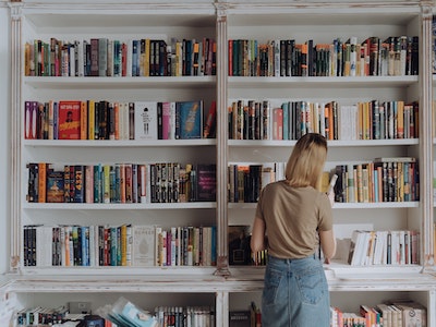 A woman organising a large book case.